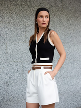 a lady wears a black vest with white bermuda shorts